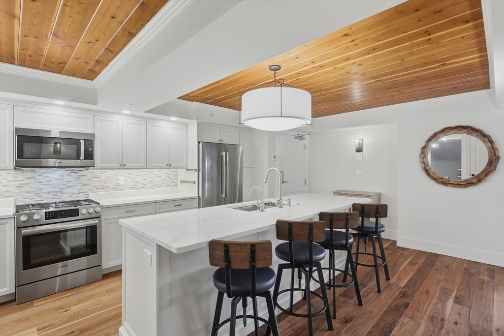 151 High Street, Unit 3B Newburyport, MA 01950 - Photo 8 of 39 a kitchen with stainless steel appliances a dining table chairs and wooden floor