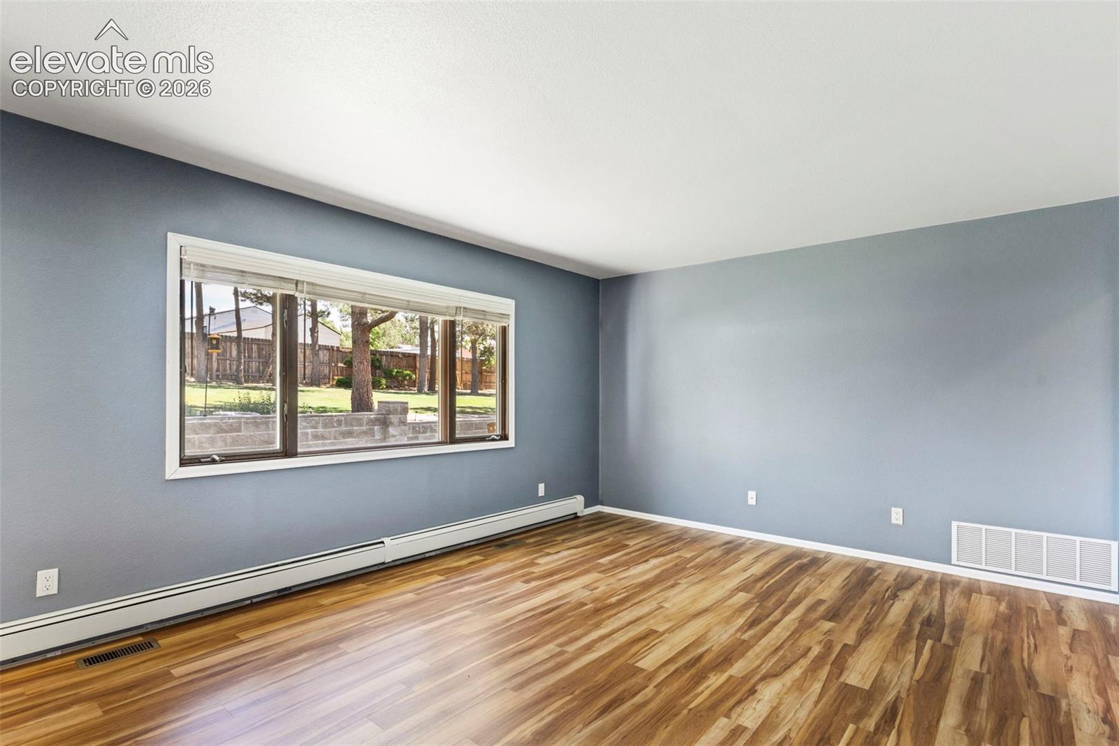 10765 Falling Star Road Fountain, CO 80817 - Photo 19 of 27 Spacious room featuring wood-finish flooring, a large picture window, and light blue wall tones