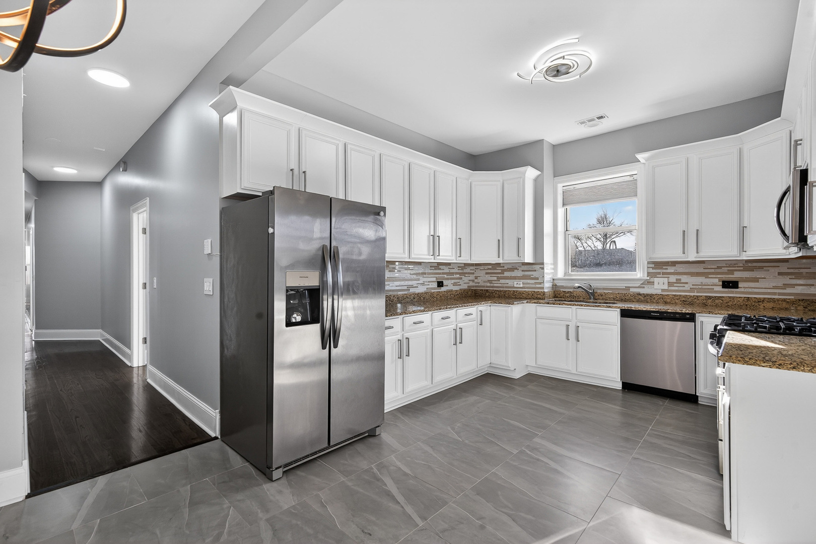 4646 South Prairie Avenue, Unit 2S Chicago, IL 60653 - Photo 18 of 32 a large kitchen with granite countertop a refrigerator oven a sink dishwasher and white cabinets next to a window