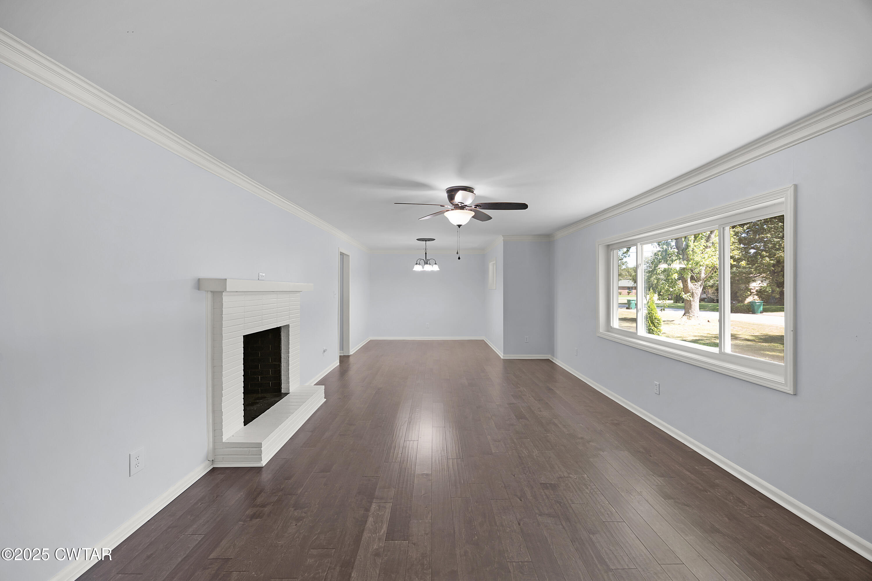 105 Dixie Lane Jackson, TN 38301 - Photo 3 of 25 an empty room with wooden floor fireplace and windows