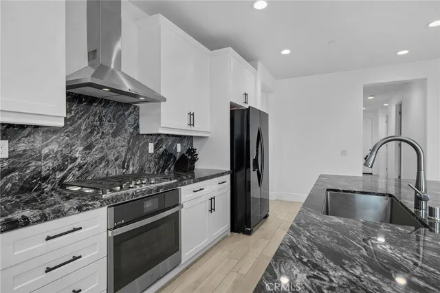 a kitchen with stainless steel appliances granite countertop a stove a sink and a refrigerator