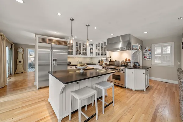 a kitchen with kitchen island stainless steel appliances a stove a sink a center island and wooden floor