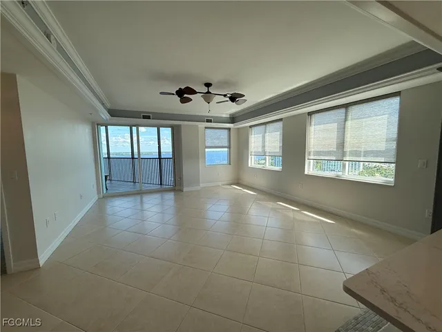 an empty room with a chandelier fan and windows