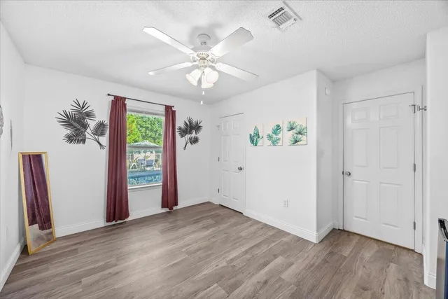 an empty room with wooden floor closet and windows