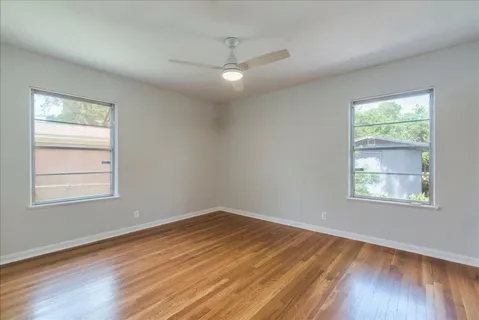 a view of an empty room with wooden floor and a window