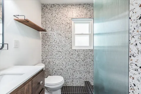a bathroom with a granite countertop toilet a sink a shower curtain
