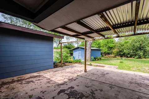 a backyard of a house with a table and chairs under an umbrella