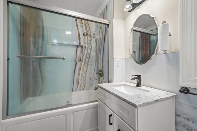 a bathroom with a granite countertop sink mirror and a bathtub