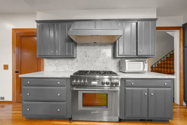 a stove top oven sitting inside of a kitchen with granite countertop wooden cabinets