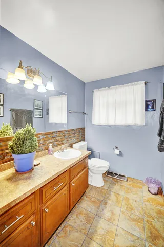 a bathroom with a granite countertop sink mirror and a toilet