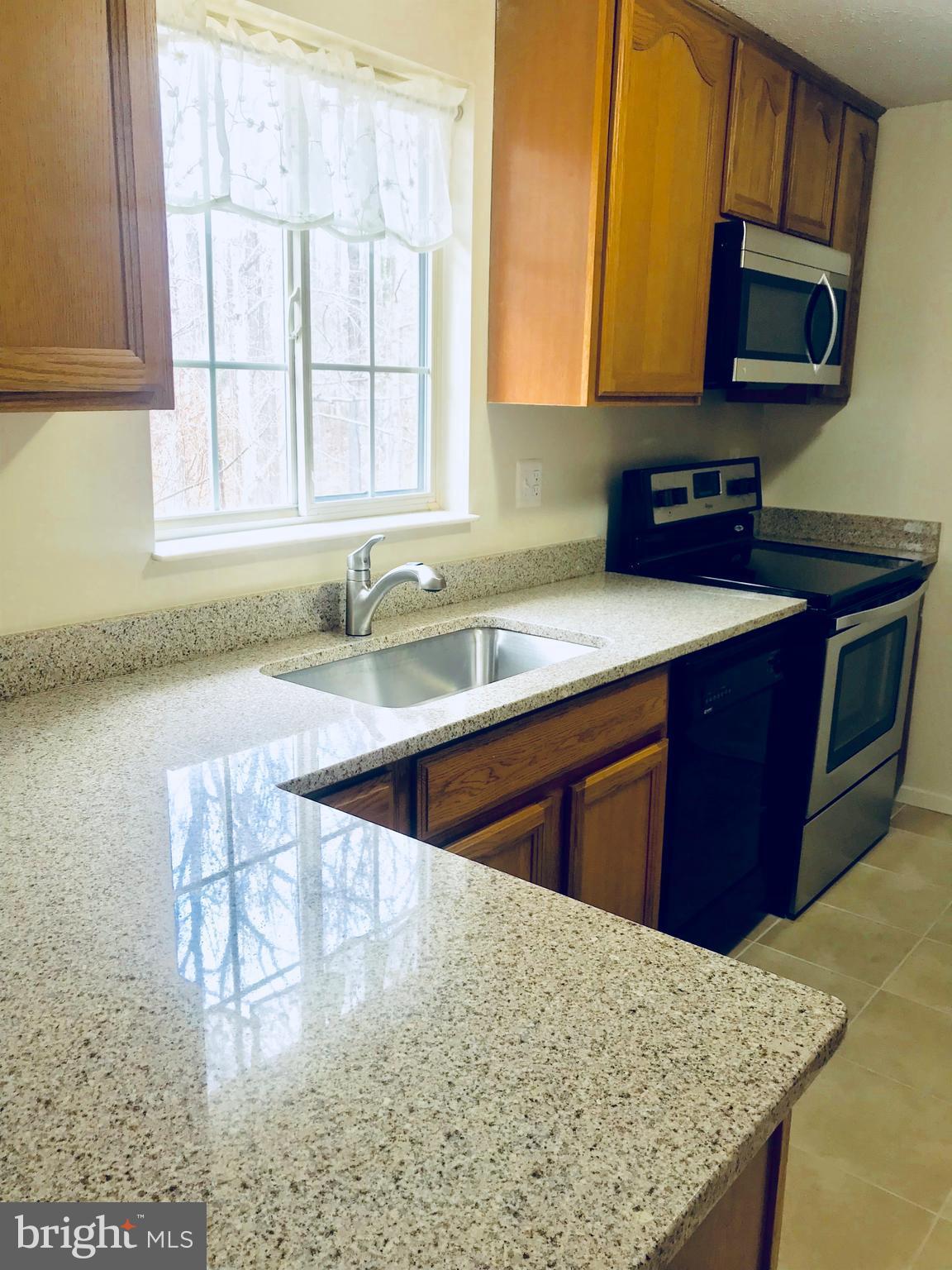 6214 Hillside Road Springfield, VA 22152 - Photo 4 of 22 a kitchen with stainless steel appliances granite countertop a sink a stove a microwave a counter top and cabinets