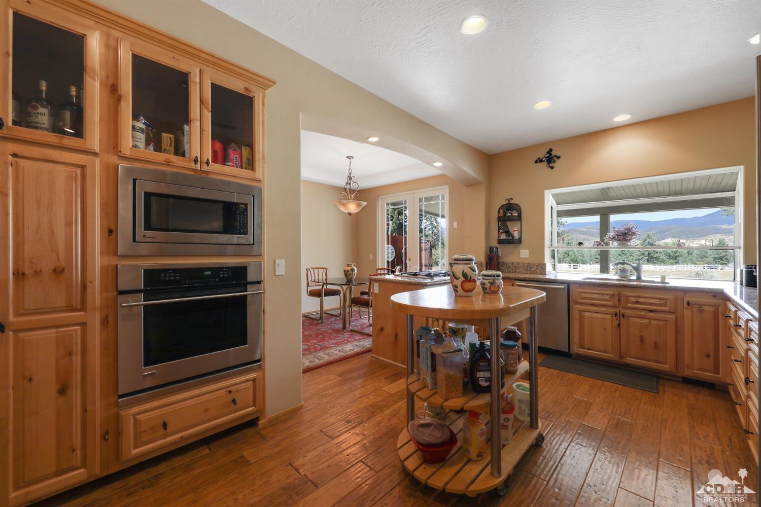 59870 Devils Ladder Road Mountain Center, CA 92561 - Photo 16 of 31 a living room with furniture a fireplace and a dining table with wooden floor