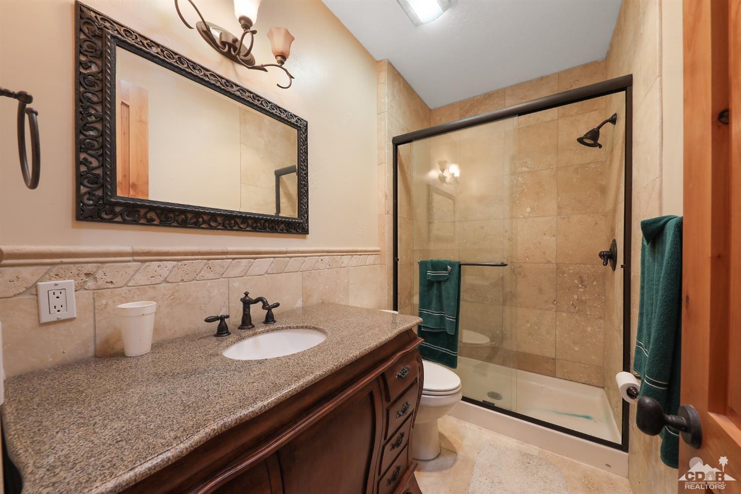 59870 Devils Ladder Road Mountain Center, CA 92561 - Photo 17 of 31 a bathroom with a granite countertop sink mirror and shower