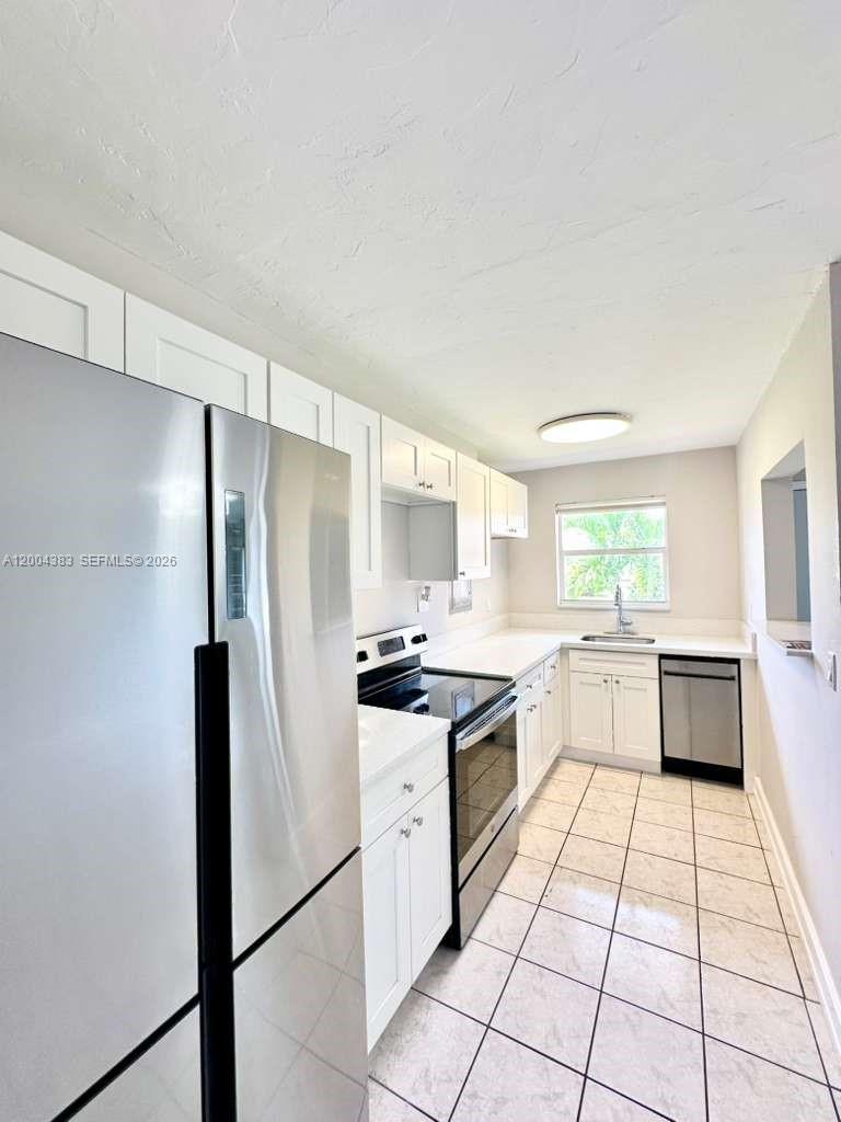 2651 Northwest 13th Street, Unit 41 Miami, FL 33125 - Photo 1 of 10 a kitchen with a refrigerator a stove a sink and a stove top oven