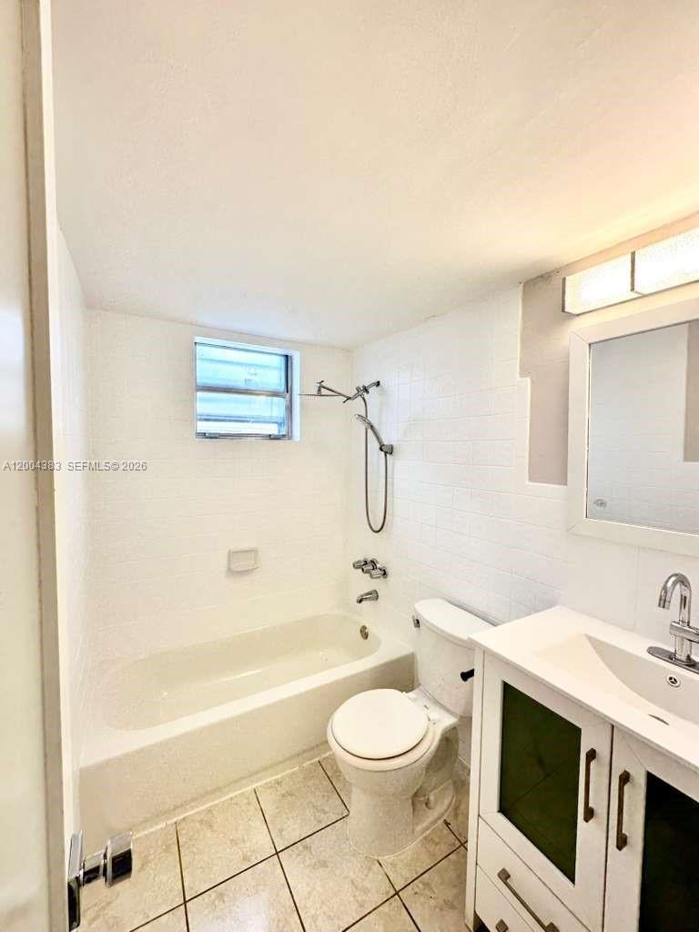 2651 Northwest 13th Street, Unit 41 Miami, FL 33125 - Photo 9 of 10 a bathroom with a toilet a sink a mirror a bathtub and shower