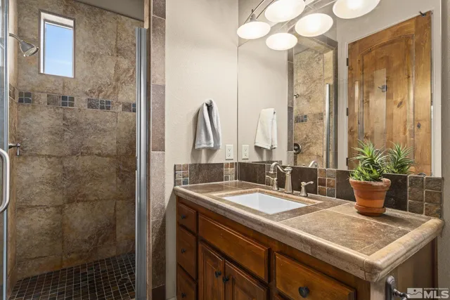 a bathroom with a granite countertop sink a mirror and a shower