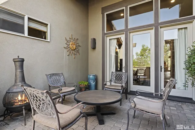 a patio with table and chairs and potted plants