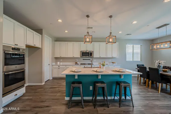 a kitchen with stainless steel appliances kitchen island granite countertop a dining table chairs and white cabinets