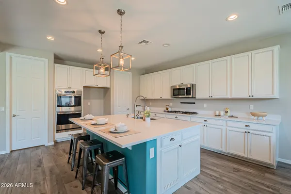 a dining room with stainless steel appliances kitchen island granite countertop a dining table chairs and a refrigerator