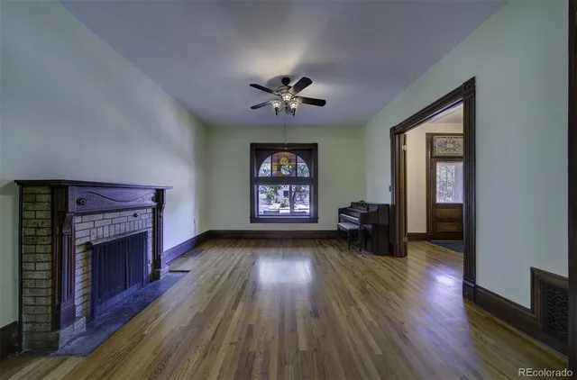 an empty room with wooden floor a fireplace and windows