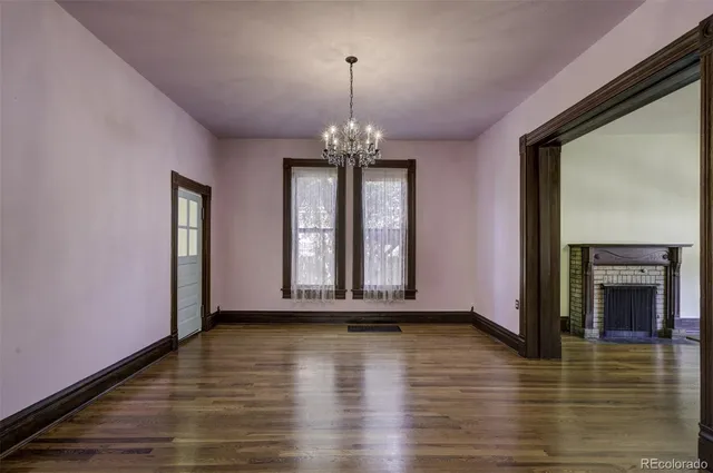 a view of a room with wooden floor fireplace and windows