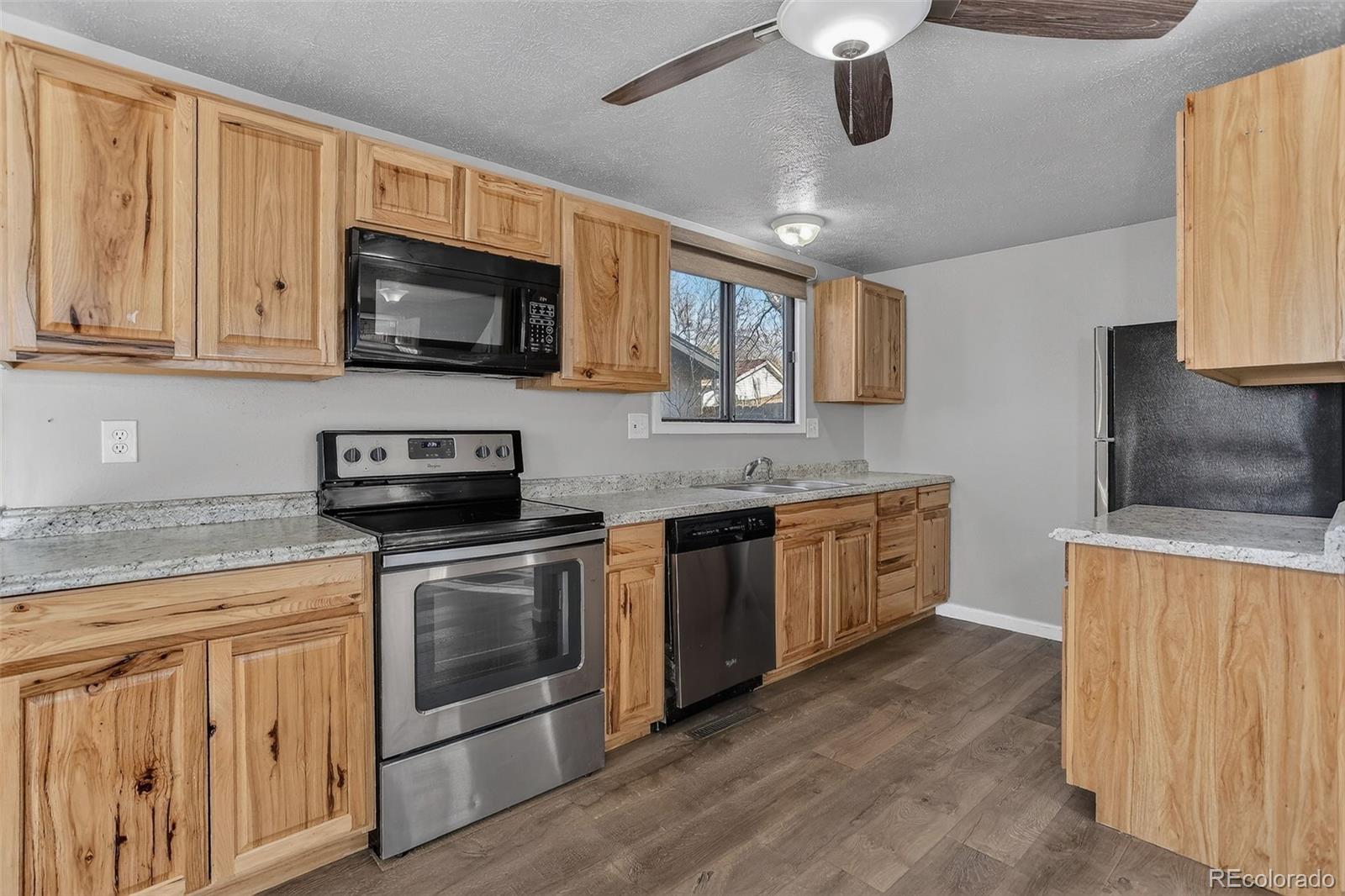9404 Pierce Street Broomfield, CO 80021 - Photo 3 of 20 a kitchen with stainless steel appliances granite countertop a sink and a stove top oven with white cabinets