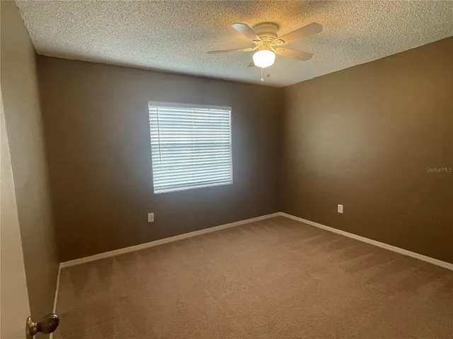 an empty room with a window and a fan