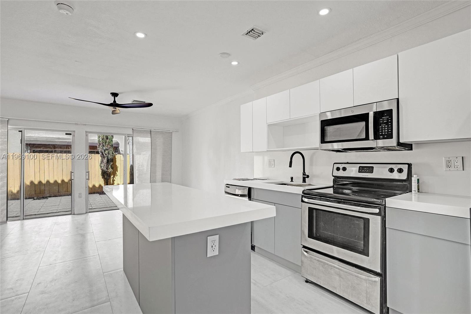 7783 Southwest 94th Lane, Unit 7783 Miami, FL 33156 - Photo 4 of 30 a kitchen with white cabinets stainless steel appliances and wooden floor