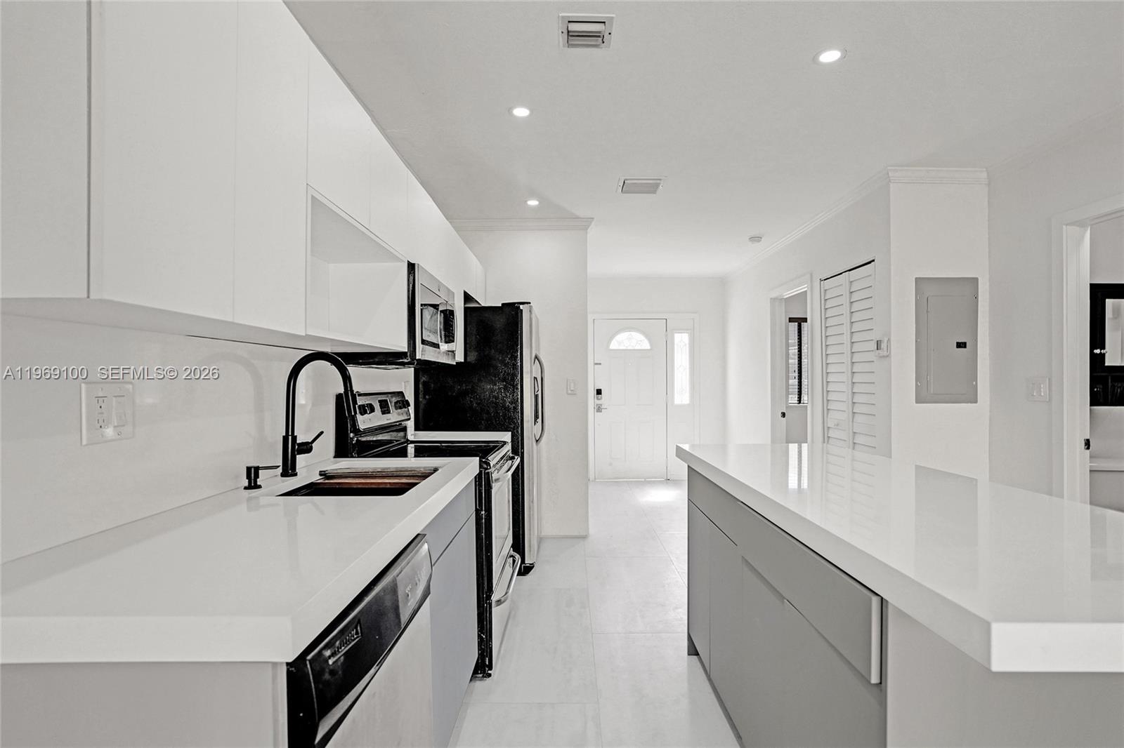 7783 Southwest 94th Lane, Unit 7783 Miami, FL 33156 - Photo 6 of 30 a kitchen with stainless steel appliances a sink dishwasher a stove and a refrigerator with wooden floor