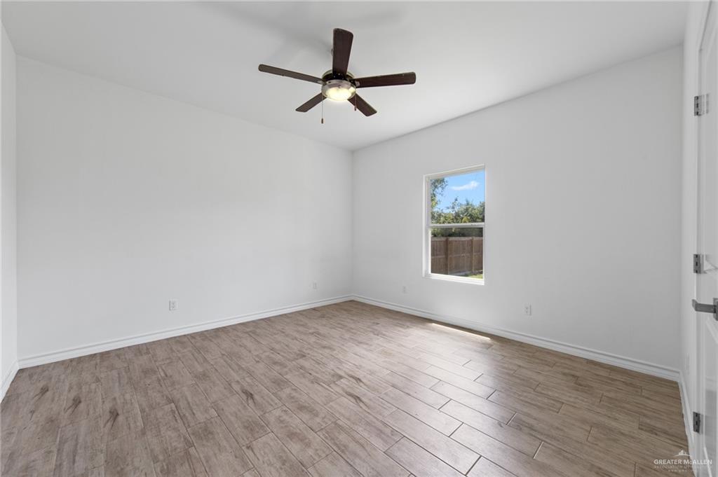 15688 Primera Road Harlingen, TX 78552 - Photo 9 of 20 an empty room with wooden floor ceiling fan and windows