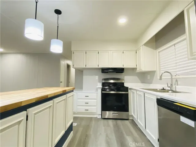 a kitchen with stainless steel appliances granite countertop a stove a sink and white cabinets