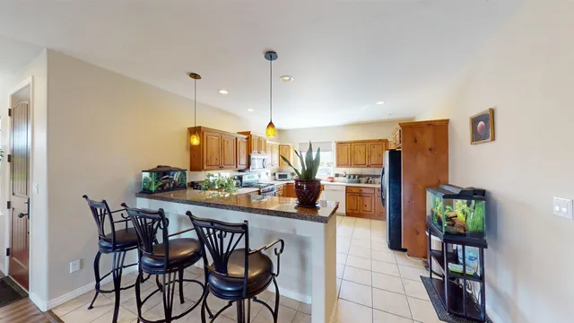a kitchen with stainless steel appliances a dining table chairs and refrigerator