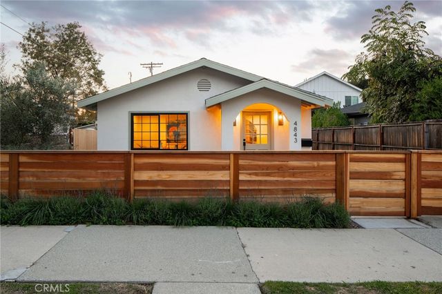 a view of a house with a small yard and wooden fence