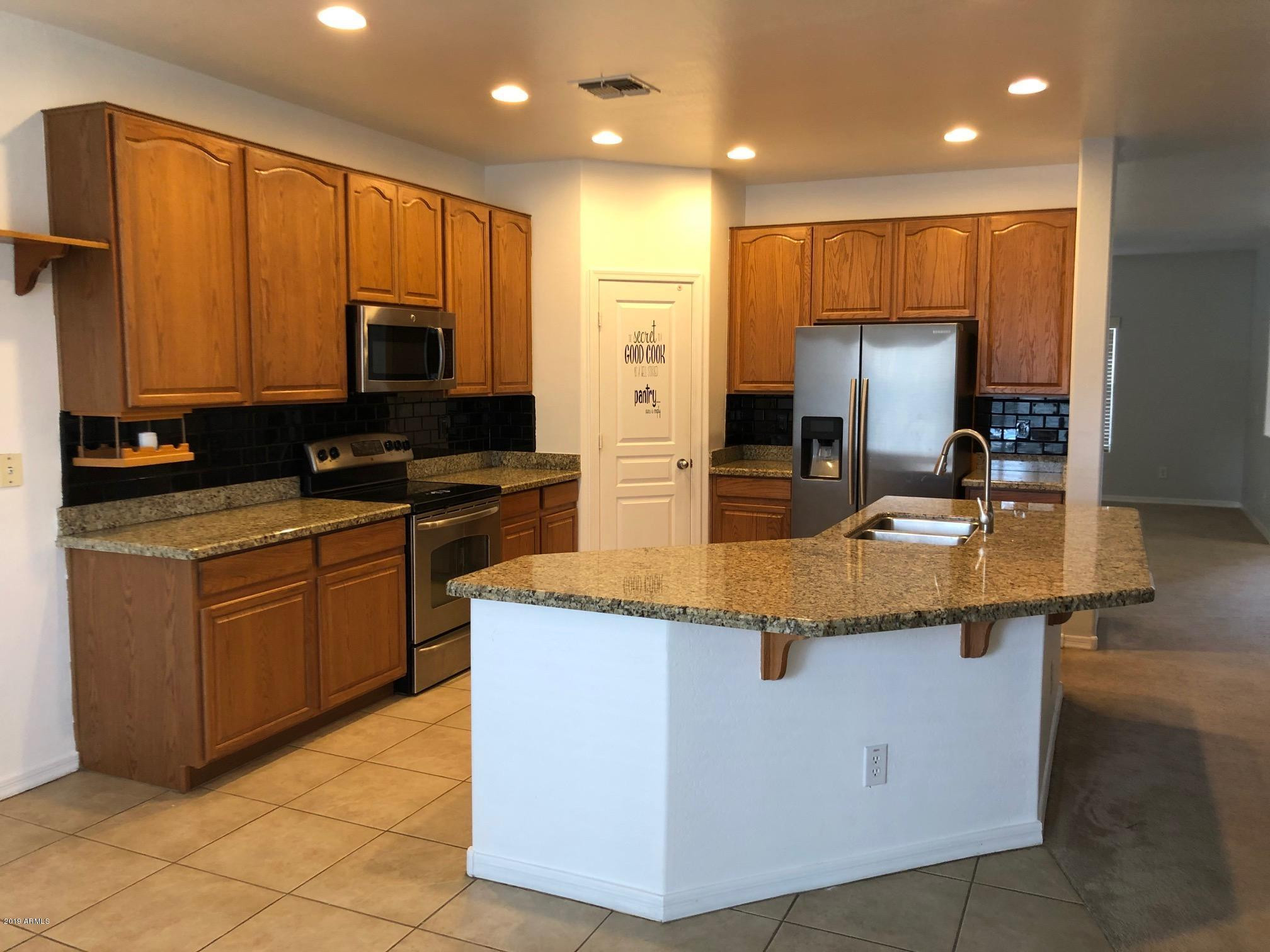 16741 West Tether Trail Surprise, AZ 85387 - Photo 4 of 20 a kitchen with stainless steel appliances granite countertop a sink counter space cabinets and a large window
