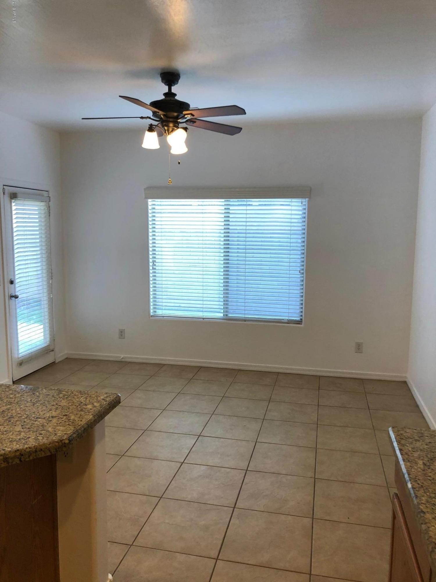 16741 West Tether Trail Surprise, AZ 85387 - Photo 5 of 20 an empty room with a chandelier fan and windows