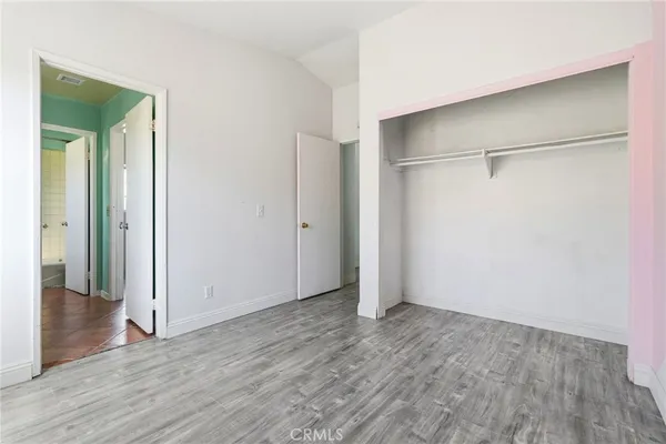 an empty room with wooden floor and a bathroom