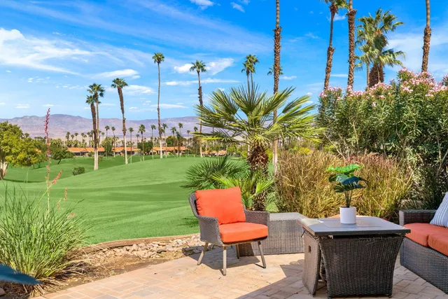 a view of a yard with a table and chairs under an umbrella