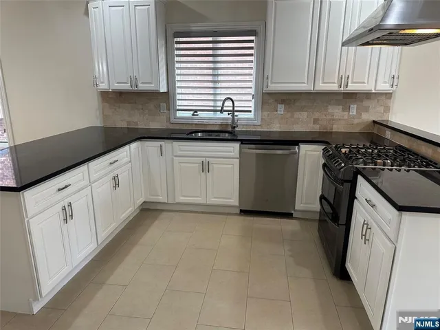 a kitchen with granite countertop a sink a stove and cabinets