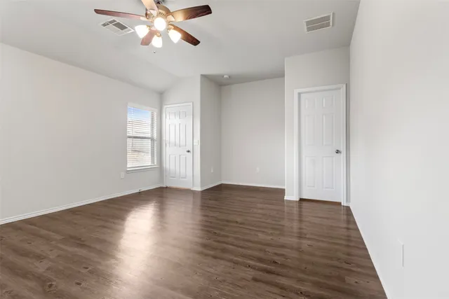 an empty room with wooden floor closet and windows