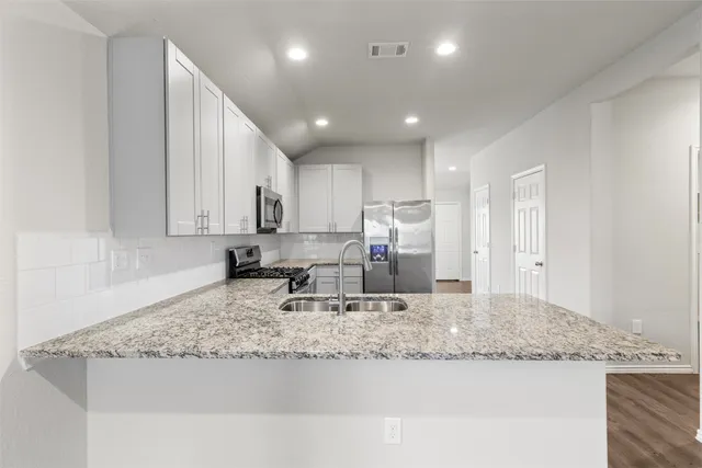 a kitchen with granite countertop kitchen island stainless steel appliances sink refrigerator and microwave