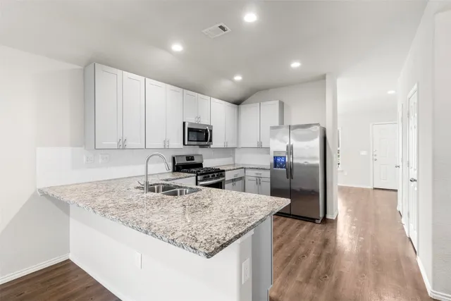 a kitchen with stainless steel appliances granite countertop a sink refrigerator and cabinets