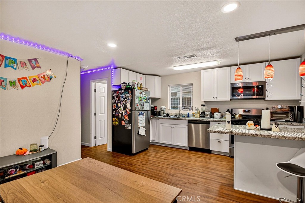 703 West 2nd Avenue Chico, CA 95926 - Photo 19 of 27 a kitchen with stainless steel appliances kitchen island granite countertop a refrigerator oven a sink dishwasher and white cabinets with wooden floor