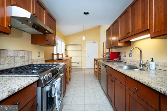 a kitchen with granite countertop a sink a stove and cabinets