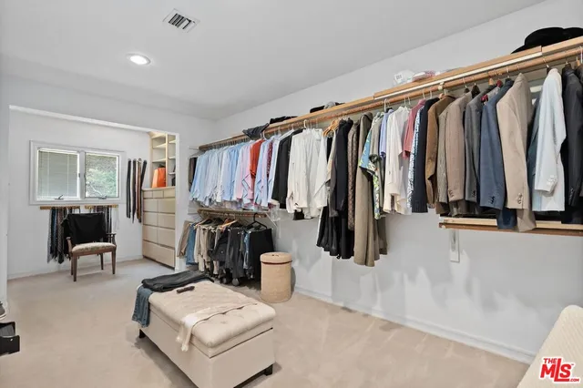 a view of walk in closet with clothes and shoes