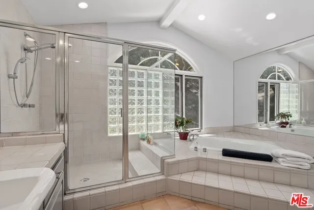 a bathroom with a tub a sink and glass door shower