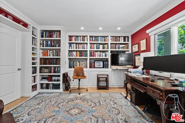 a view of a workspace with bookshelf and a window