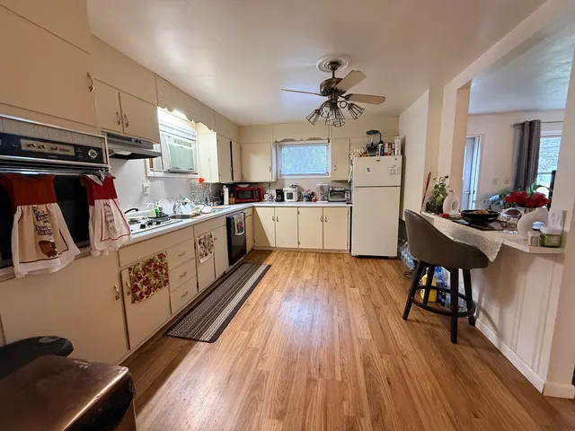a kitchen with refrigerator and wooden floor