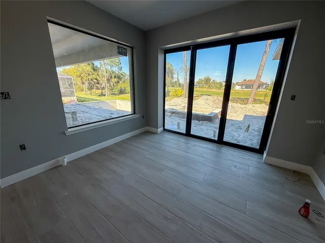 a view of an empty room with wooden floor and windows