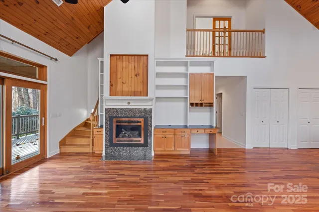 a view of an empty room with chandelier fan and wooden floor