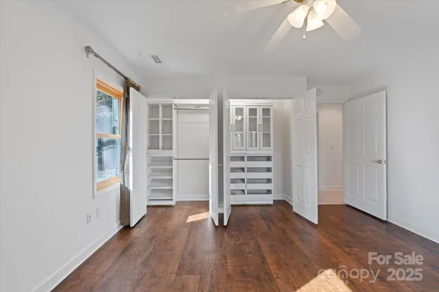 a view of an empty room with wooden floor and a ceiling fan